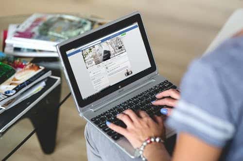 woman with laptop open on facebook page