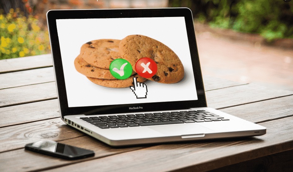 Computer on wooden table-mobile-2 cookies on screen-1 with green tick-1 with red cross